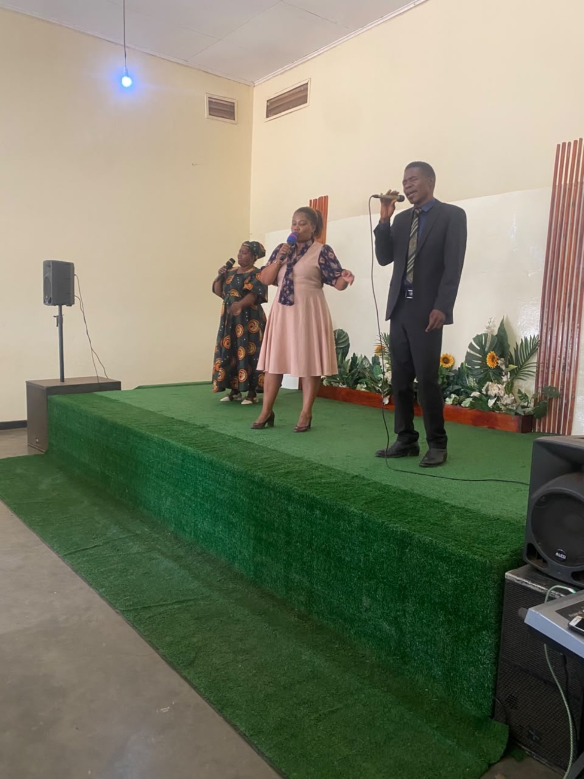 Three singers leading worship from the church platform.