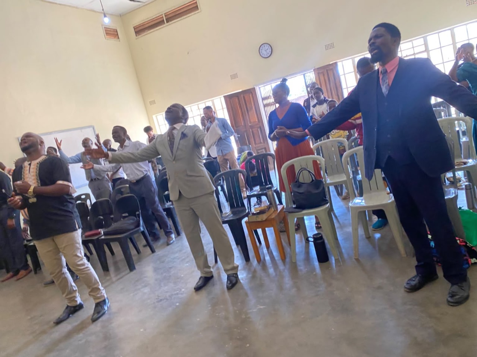 Congregation members standing with open arms during worship.