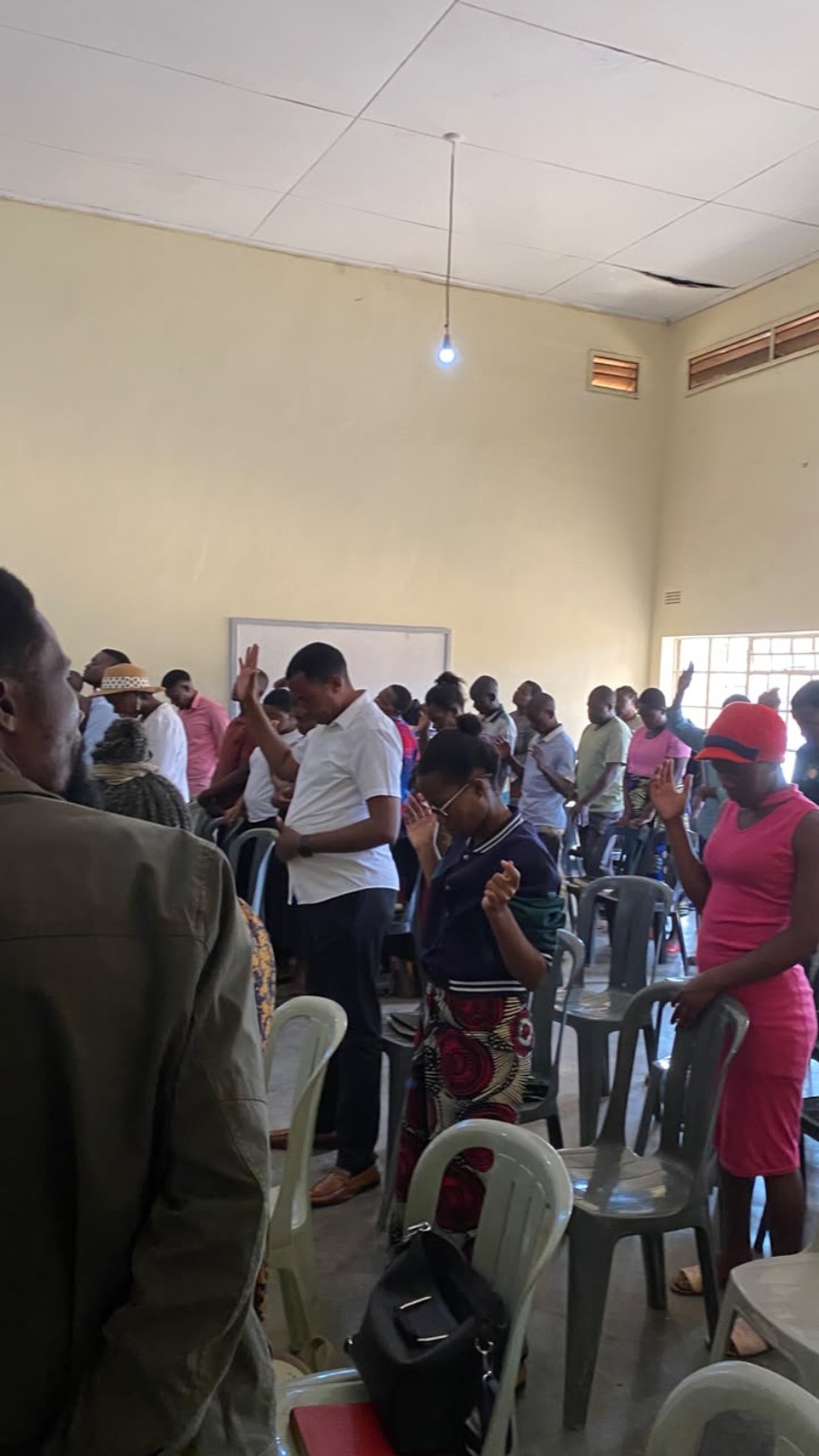 Congregation members standing together in prayer.