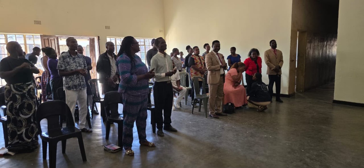 A wide view of the congregation standing together inside the church hall.