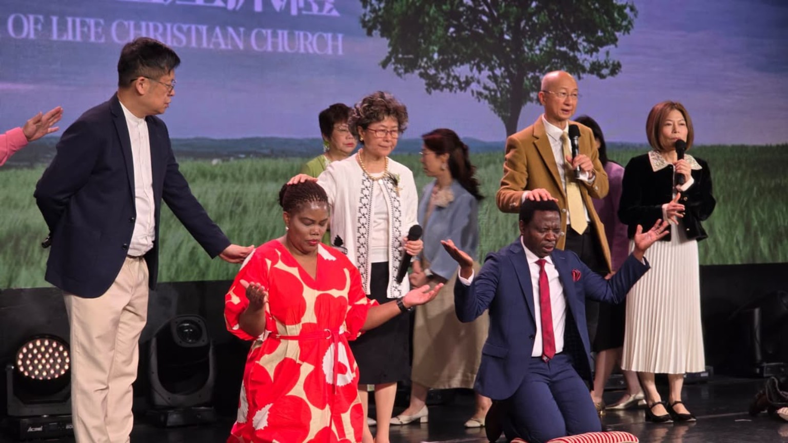 A group gathered on a church stage with several members kneeling at the front.