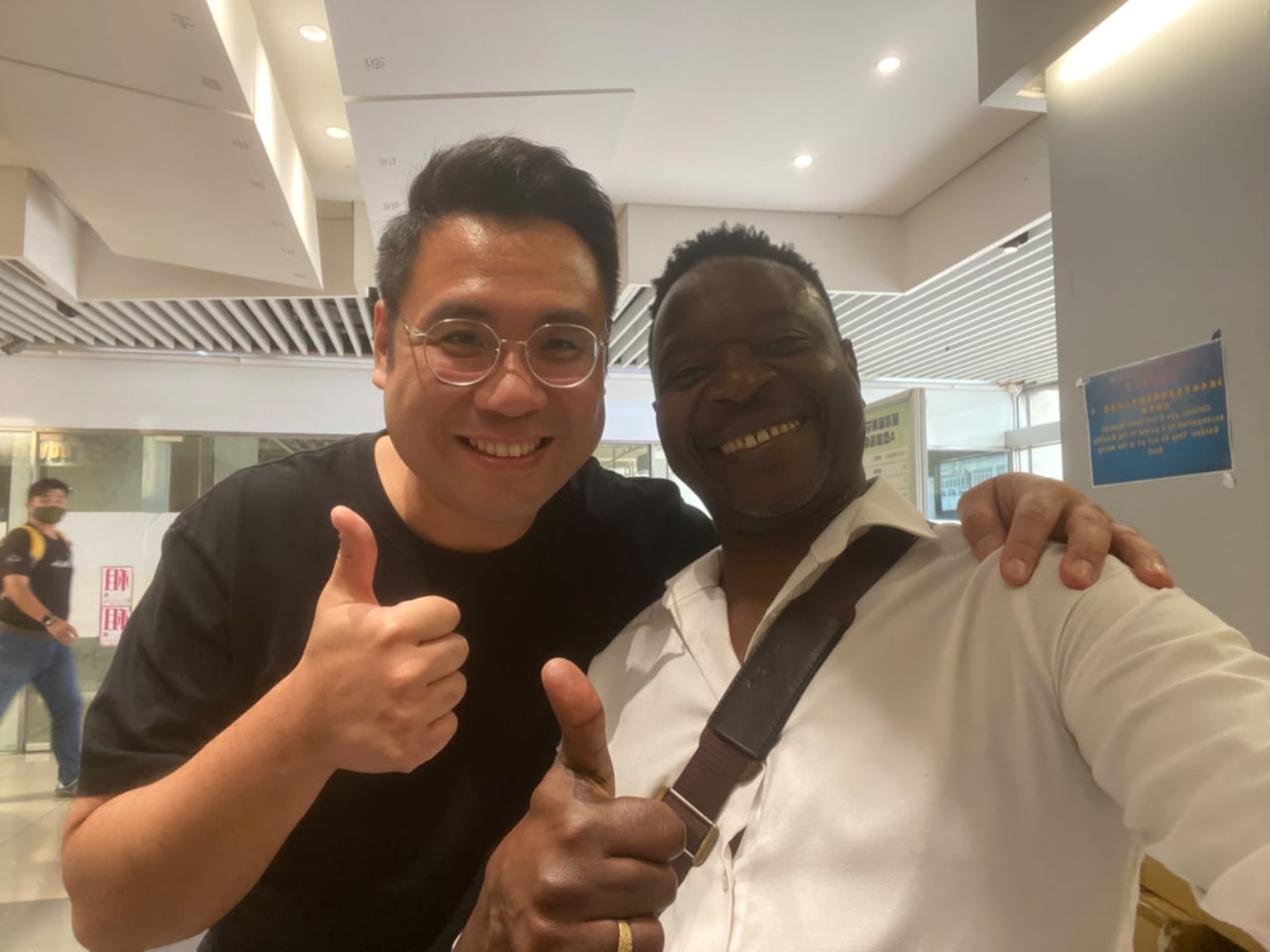 Two smiling men standing together with an arm around a shoulder.