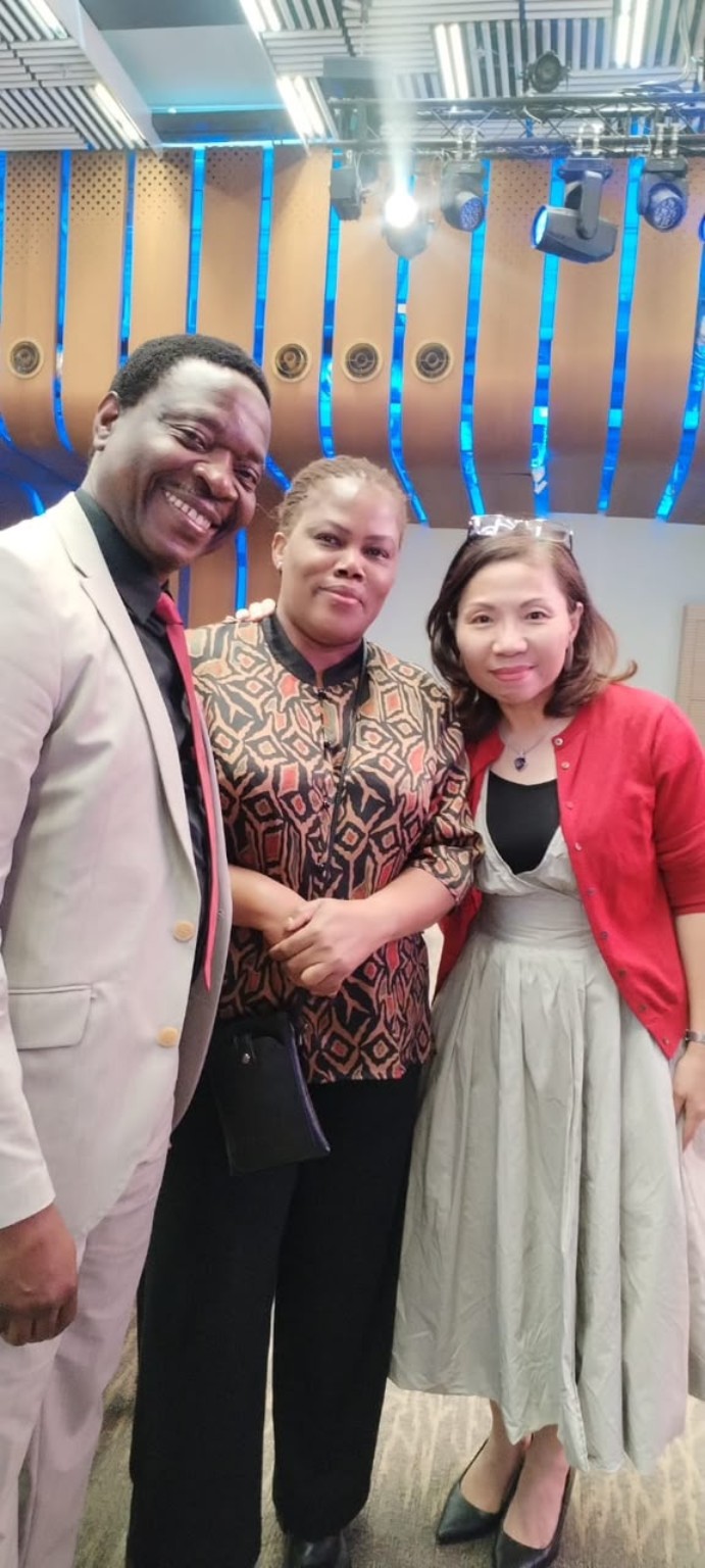 Three smiling people posing together in a church auditorium.
